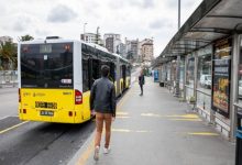 Metrobüs durağında çekilen fotoğrafta, sarı renkli bir metrobüs peronda yolcu indirirken bir kişi durağa doğru yürüyerek araca yaklaşmaya çalışıyor. Uzun ve geniş peron alanında durak yapıları, reklam panoları ve şehir binaları arka planda görülüyor. Görsel, toplu taşımada özellikle engelli bireylerin erişim ve ulaşım sırasında karşılaştığı zorluklara dikkat çeken bir atmosfer yansıtıyor.