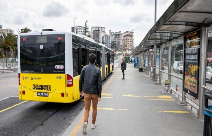 Metrobüs durağında çekilen fotoğrafta, sarı renkli bir metrobüs peronda yolcu indirirken bir kişi durağa doğru yürüyerek araca yaklaşmaya çalışıyor. Uzun ve geniş peron alanında durak yapıları, reklam panoları ve şehir binaları arka planda görülüyor. Görsel, toplu taşımada özellikle engelli bireylerin erişim ve ulaşım sırasında karşılaştığı zorluklara dikkat çeken bir atmosfer yansıtıyor.