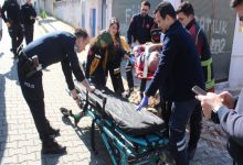Sağlık ekipleri ve polis memurları hastayı sedyeye taşıyor.