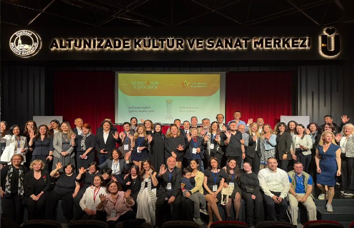 Altunizade Kültür ve Sanat Merkezi sahnesinde çekilen toplu fotoğrafta, farklı yaş gruplarından çok sayıda kişi bir arada poz veriyor. Arkadaki ekranda “Bağımsız Yaşam ve Eşitlik Zirvesi” yazısı yer alırken, katılımcıların çoğu kameraya gülümseyerek el sallıyor. Fotoğraf, kapsayıcılık ve dayanışma temalı geniş katılımlı bir etkinlik atmosferini yansıtıyor.