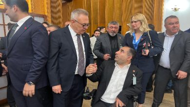 TBMM’de düzenlenen toplantı sırasında çekilen fotoğrafta, takım elbiseli kalabalık bir grup ayakta sohbet ediyor. Ön planda tekerlekli sandalyedeki bir erkek ile bir milletvekili tokalaşarak konuşurken görülüyor. Fotoğraf, Engelliler Haftası kapsamında Meclis’te gerçekleşen buluşmanın samimi ve yoğun atmosferini yansıtıyor.
