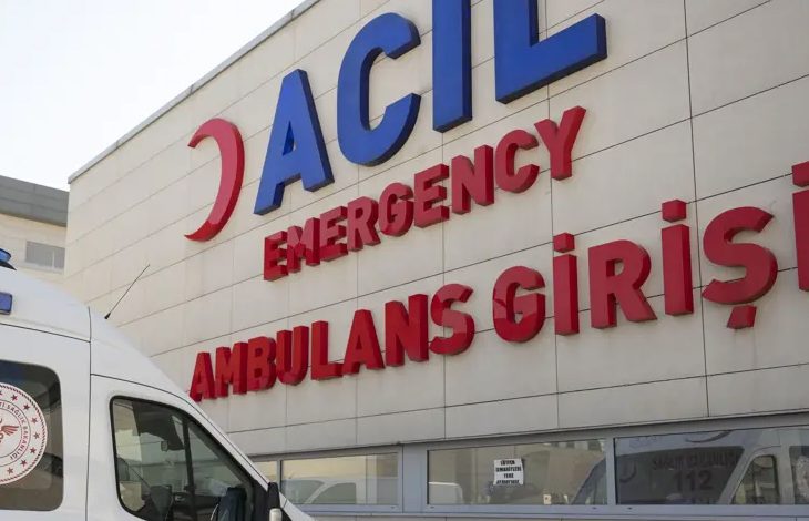 Bir hastanenin acil girişinde beyaz bir ambulans duruyor.