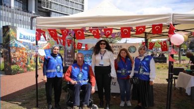 EngelsizFest: Üreten Eller Kermesi standı önünde, Türk bayraklarıyla süslenmiş tentesi altında poz veren görevliler ve katılımcılardan oluşan 5 kişilik bir gruptur. Etkinlikteki dayanışma atmosferini yansıtmaktadır.