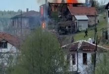 Kırsal bir yerleşim alanında bulunan iki katlı ahşap bir evden yoğun alev ve duman yükseliyor. Çevredeki evler ve ağaçların arasından görülen yangın sırasında bazı kişilerin olay yerine doğru ilerlediği dikkat çekiyor.