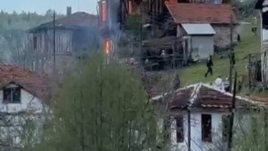 Kırsal bir yerleşim alanında bulunan iki katlı ahşap bir evden yoğun alev ve duman yükseliyor. Çevredeki evler ve ağaçların arasından görülen yangın sırasında bazı kişilerin olay yerine doğru ilerlediği dikkat çekiyor.