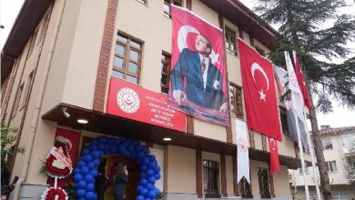 Bir kamu binasının dış cephesinde Türk bayrakları ve Mustafa Kemal Atatürk posterleri asılı görülüyor. Giriş kısmı mavi balonlarla süslenirken, binanın üzerinde “Kavacık Engelli Aktif Yaşam Merkezi Müdürlüğü” tabelası yer alıyor. Görsel, resmi açılış ya da etkinlik atmosferini yansıtıyor.