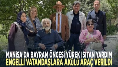 Altı kişilik bir grup var; iki kişi tekerlekli sandalyede, diğerleri ayakta ve hepsi birlikte poz veriyor.