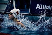 Bir para yüzme sporcusu havuzda yarış sonrası suyun içinde görülüyor. Bonesinde Türk bayrağı ve “S. Boyacı” yazısı yer alırken, etrafa sıçrayan su damlaları mücadele anının dinamizmini yansıtıyor. Arka planda yarış organizasyonuna ait sponsor panoları dikkat çekiyor.