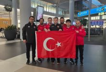Türkiye İşitme Engelliler Satranç Milli Takımı ve teknik kafile Türk bayrağı tutarak havaalanında poz veriyor.