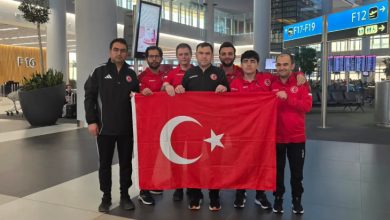 Türkiye İşitme Engelliler Satranç Milli Takımı ve teknik kafile Türk bayrağı tutarak havaalanında poz veriyor.