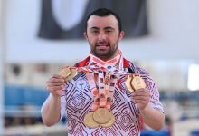 Milli sporcu Alper Öztürk, boynunda bulunan kazandığı madalyaları tutarak poz veriyor.