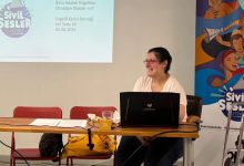 Görselde, Sivil Sesler Festivali kapsamında düzenlenen "İklim Adaleti Engelliler Olmadan Olabilir mi?" başlıklı atölyeyi yürüten İdil Seda Ak bir masanın arkasında otururken görülüyor. Önündeki dizüstü bilgisayar üzerinden sunum yapan Ak gülümserken, arkasındaki projeksiyon ekranında atölyenin başlığı ve tarih bilgisi yer alıyor. Sağ tarafta ise Sivil Sesler Festivali afişi görülüyor.