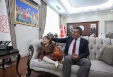 Görme engelli Nil Korkmaz bağlama tutarak Milli Eğitim Bakanı Yusuf Tekin ile koltukta oturuyor.