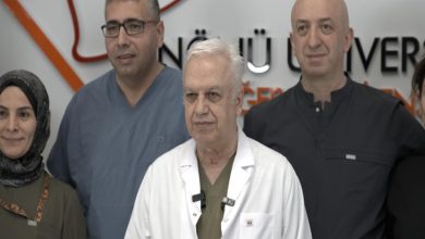 Görselde, bir sağlık kuruluşunda çekilmiş toplu bir fotoğraf yer alıyor. Ön sırada beyaz önlük giyen yaşlı bir doktor bulunurken, arkasında ve yanında sağlık çalışanları görülüyor. Arka planda hastane veya tıp merkezi logosunun bir bölümü yer alıyor. Fotoğraftaki kişiler kameraya dönük şekilde poz veriyor ve görüntü, tıbbi bir başarı ya da basın açıklaması sonrası çekilmiş ekip fotoğrafı izlenimi veriyor.