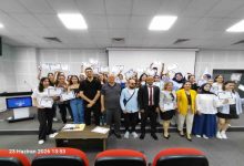Bir konferans salonunda çekilen toplu fotoğrafta, çok sayıda genç ellerinde sertifikalarıyla poz veriyor. Ön sırada eğitmenler ve organizasyon temsilcileri yer alırken, katılımcılar başarılarını kutlayan neşeli bir görünüm sergiliyor. Görsel, eğitim programının tamamlanması sonrasında düzenlenen sertifika törenini yansıtıyor.