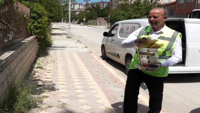 Açık yeşil üniformalı belediye personeli erkek, beslenme gıdalarını elinde taşıyor.