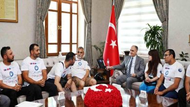 Resmî bir makam odasında gerçekleştirilen ziyarette, engelli sporcular ve proje temsilcileri bir araya gelmiş durumda. Türk bayrağının bulunduğu odada, takım tişörtleri giyen katılımcılar bir yetkiliyle görüşürken görülüyor. Görsel, engelli bireylerin yer aldığı bir spor veya sosyal sorumluluk projesine ilişkin resmî kabul ve destek sürecini yansıtıyor.