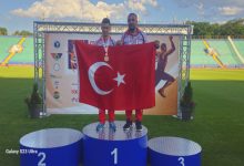 Özel Milli Atlet Muhammed Eren Uysal erkek antrenörü ile birincilik kürsüsünde Türk bayrağı açarak poz veriyor.