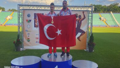 Özel Milli Atlet Muhammed Eren Uysal erkek antrenörü ile birincilik kürsüsünde Türk bayrağı açarak poz veriyor.
