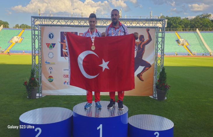 Özel Milli Atlet Muhammed Eren Uysal erkek antrenörü ile birincilik kürsüsünde Türk bayrağı açarak poz veriyor.