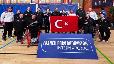 Turnuvaya katılan Para Badminton Milli Takımı ve teknik heyet, Türk Bayrağı açarak poz veriyor.