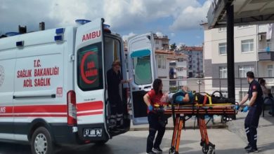 Bir ambulansın yanında sağlık ekiplerinin sedye üzerindeki yaralı bir kişiye müdahale ettiği görülüyor. Acil sağlık personeli, yaralıyı ambulansa taşımaya hazırlanırken olayın bir sağlık kuruluşu veya hastane çevresinde gerçekleştiği anlaşılıyor. Görsel, trafik kazası sonrası yürütülen acil müdahale sürecini yansıtıyor.