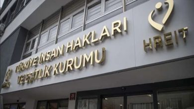 Görselde, Türkiye İnsan Hakları ve Eşitlik Kurumu'nun (TİHEK) hizmet binasının dış cephesi ve giriş kısmı yer almaktadır. Beyaz bir zemin üzerine, kabartmalı ve altın sarısı renkte büyük harflerle "TÜRKİYE İNSAN HAKLARI VE EŞİTLİK KURUMU" yazmaktadır. Bu yazının sağ tarafında kurumun amblemi ve altında İngilizce kısaltması olan "HREIT" ibaresi bulunur. Sol alt köşede ise kurumun küçük bir logosu yer almaktadır. Binanın girişinde camekanlı kapılar ve üst katlara ait pencereler görünmektedir.