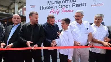 Fotoğrafta, parkın açılış töreninde kırmızı kurdele kesilirken zihinsel engelli Muhammet mikrofonla konuşuyor. Çevresinde belediye yetkilileri ve davetliler yer alırken, arka planda parkın açılışına ait afiş görülüyor.