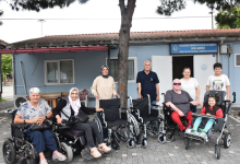 Karadeniz Omurilik Felçlileri Derneği önünde çekilen fotoğrafta, tekerlekli sandalye ve akülü sandalye kullanan bireyler ile yakınları, teslim edilen tekerlekli sandalyelerle birlikte toplu halde objektife poz veriyor. Arka planda dernek binasının girişi ve tabelası yer alıyor.