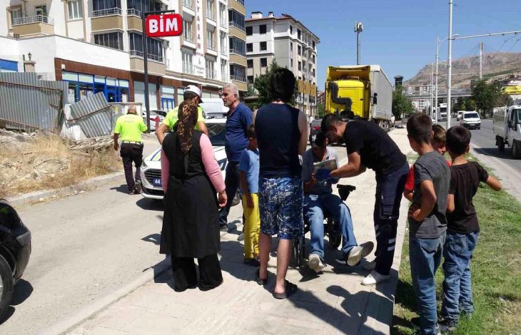Akülü sandalyede bulunan yayanın etrafında vatandaşlar ve polis memurları bulunuyor.