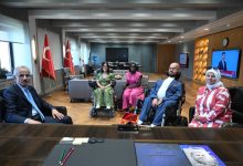 Bakan Uraloğlu, makamında misafir koltuğunda oturuyor ve karşısında bulunan milli boccia sporcuları Emre ve Fulya Vural ile birlikte, farklı sporcuların da yer aldığı buluşmada, makam odasında toplu hatıra fotoğrafı çekiliyor.