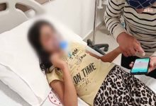 Darp edilen otizmli kız çocuğun yüzü buzlanmış fotoğrafta, oksijen maskesi takılı olarak hastane yatağında uzanıyor ve bir yakını elini tutarak telefon kullanıyor.