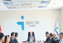 Görselde, İŞKUR Denizli İl Müdürlüğü toplantı salonunda düzenlenen bir değerlendirme toplantısı görülüyor. Masanın başında oturan yetkiliye karşılıklı olarak katılımcılar yer alırken, duvarda İŞKUR Denizli logosu, masada ise Türk bayrağı ve kurum bayrakları bulunuyor. Resmî bir toplantı ortamı dikkat çekiyor.