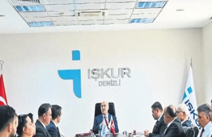 Görselde, İŞKUR Denizli İl Müdürlüğü toplantı salonunda düzenlenen bir değerlendirme toplantısı görülüyor. Masanın başında oturan yetkiliye karşılıklı olarak katılımcılar yer alırken, duvarda İŞKUR Denizli logosu, masada ise Türk bayrağı ve kurum bayrakları bulunuyor. Resmî bir toplantı ortamı dikkat çekiyor.