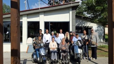 Engelli sivil toplum kuruluşlarının temsilcileri güneşli bir havada anı fotoğrafı çektiriyor.