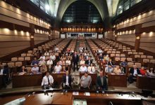 Saraçhane İBB Meclis Salonu'nda, Başkan Vekili Nuri Aslan ayakta bulunurken, kurum yöneticileri ve engelli derneklerin temsilcileri meclis sandalyelerinde oturarak hatıra fotoğrafı veriliyor.