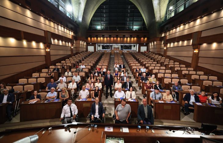 Saraçhane İBB Meclis Salonu'nda, Başkan Vekili Nuri Aslan ayakta bulunurken, kurum yöneticileri ve engelli derneklerin temsilcileri meclis sandalyelerinde oturarak hatıra fotoğrafı veriliyor.
