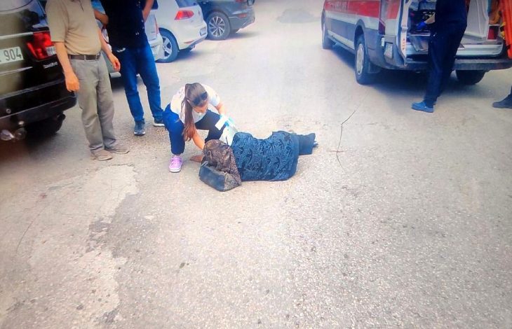 Sağlık personeli kadın, yerde uzanan kadına müdahale ediyor.