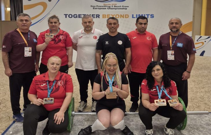 Madalya kazanan sporcular ile teknik heyet bir arada poz veriyor.