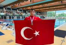 Özel Sporcu Bilge Kağan Yılgın, boynunda madalyası ve elinde Türk bayrağı tutarak poz veriyor.