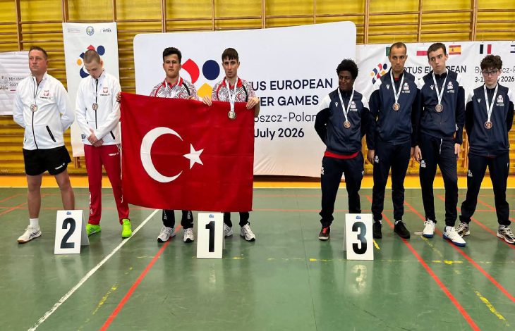 Özel sporcular Burak Burç ve Efe Gümüş, Türk bayrağı tutarak madalya töreninde rakiplerinin yanında poz veriyor.