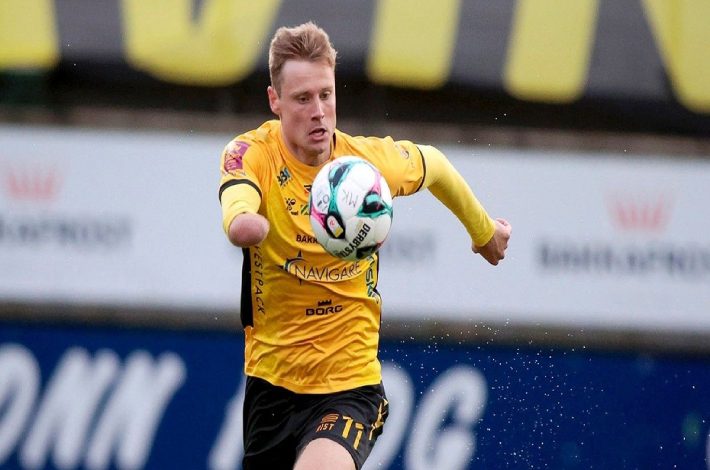 Runavik forması giyen sağ kolu ampute futbolcu Marius Lindh, göğsünün önünde top sürüyor.