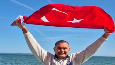 Ultra maraton yüzücüsü Tuna Tunca, Türk Bayrağını havaya kaldırıp poz veriyor.