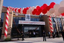Kırmızı ve beyaz balonlarla süslenen Karatay Engelli Aktif Yaşam Merkezi'nin giriş cephesi, açılış organizasyonu kapsamında hazırlanan tören alanı ve katılımcılarla birlikte görüntülenmektedir.