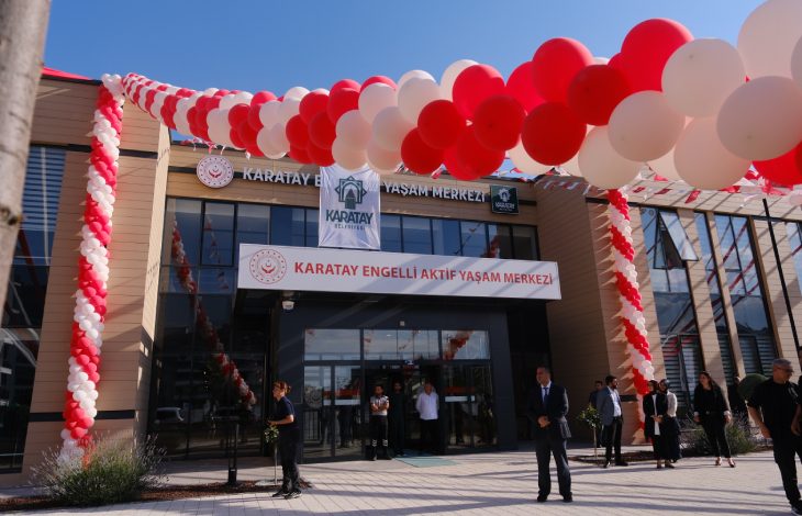 Kırmızı ve beyaz balonlarla süslenen Karatay Engelli Aktif Yaşam Merkezi'nin giriş cephesi, açılış organizasyonu kapsamında hazırlanan tören alanı ve katılımcılarla birlikte görüntülenmektedir.