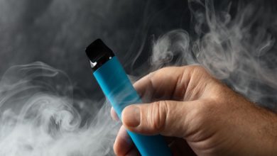 Dumanlar içinde elde tutulan mavi elektronik sigara.