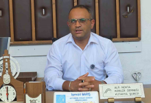 Fotoğrafta, Altı Nokta Körler Derneği Kütahya Şubesi Başkanı İsmail Barış, masasının başında açıklama yaparken görülüyor. Masada derneğe ait isimlikler, bir masa saati ve çeşitli ofis eşyaları bulunurken, arka planda ahşap kaplamalı duvar yer alıyor.