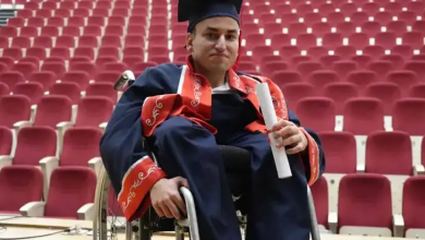 Fotoğrafta, tekerlekli sandalye kullanan Abdullah mezuniyet cübbesi ve kepiyle üniversite amfisinde oturuyor. Elinde diplomasını tutan Abdullah'ın arka planında kırmızı koltuklarla dolu konferans salonu görülüyor.