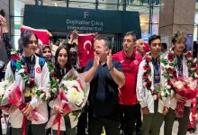 Türkiye İşitme Engelliler Spor Federasyonu Başkanı Dursun Gözel ile milli sporcular, çiçek ve Türk bayrakları tutarak yan yana duruyor.