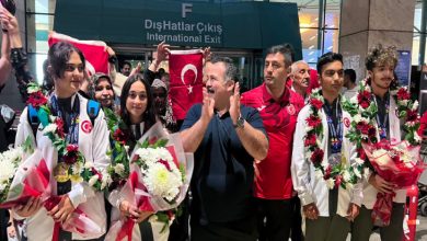 Türkiye İşitme Engelliler Spor Federasyonu Başkanı Dursun Gözel ile milli sporcular, çiçek ve Türk bayrakları tutarak yan yana duruyor.